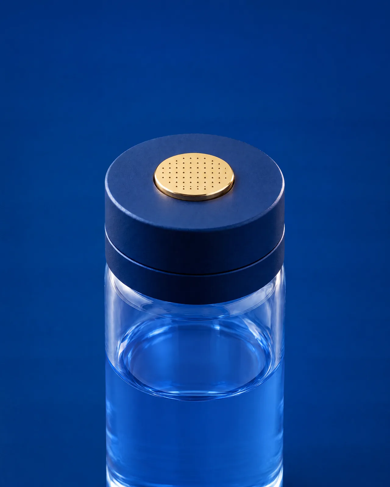 Micro-infusion head with a gold micro-needle pad, fitted on a clear base vial of blue serum.