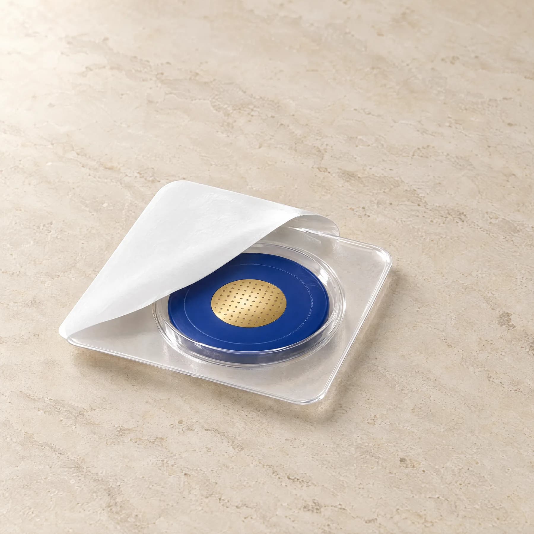 A used micro-infusion head back in its clear blister, the lid folded over it.