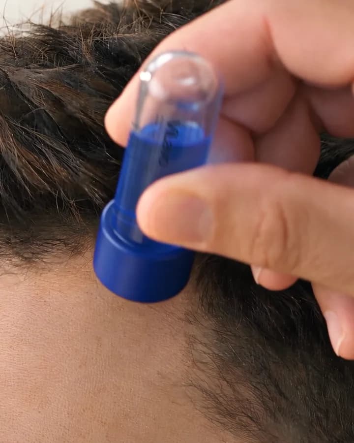 A man's hand stamps the ViLavo base vial gently along his hairline.